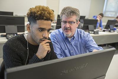 计算机科学 professor works with student in computer lab