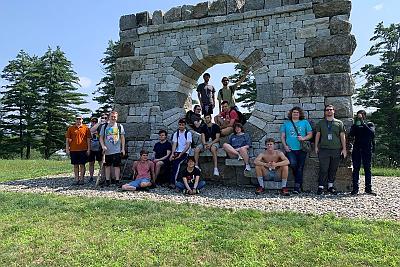 Landmark College hiking class students posing in front of a large stone sculpture in Putney, Vermont.